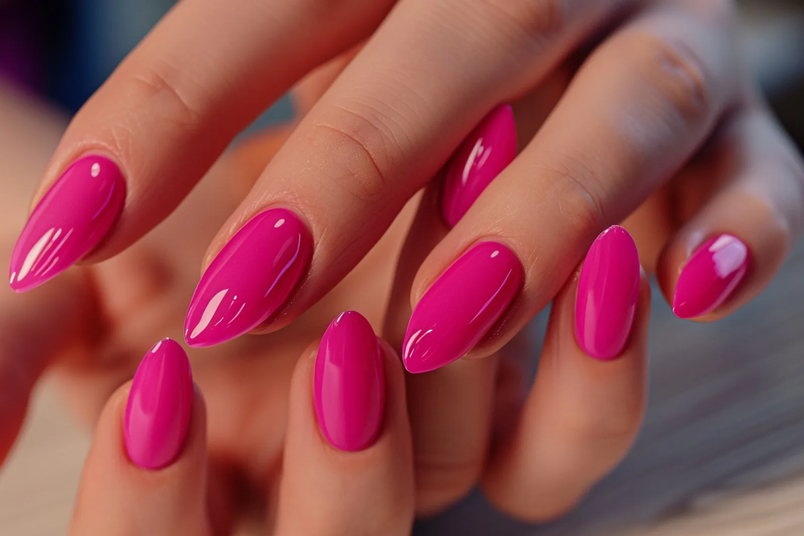 Une personne pose des faux-ongles à son bureau de manucure, avec des outils alignés et une lumière naturelle douce.