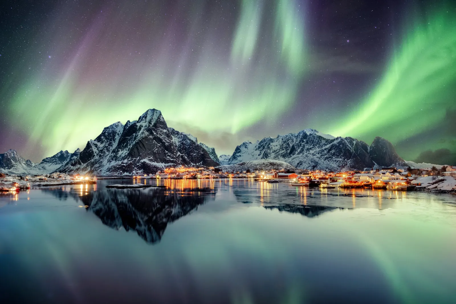 Vue panoramique d’un fjord islandais avec route côtière, montagnes abruptes et lumière naturelle dramatique.