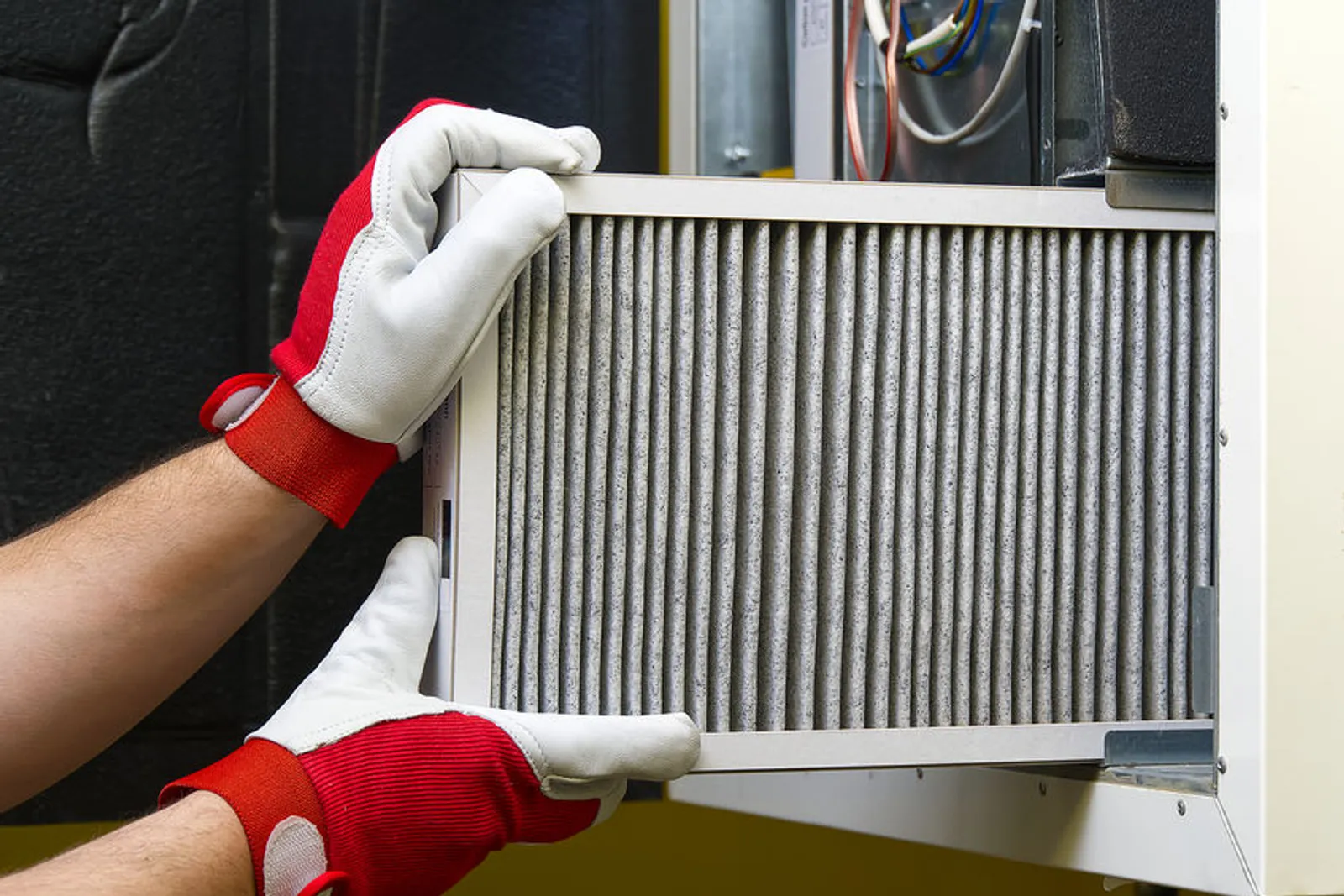 Un technicien nettoie des conduits de ventilation avec un système d’aspiration et une caméra d’inspection dans une pièce protégée.