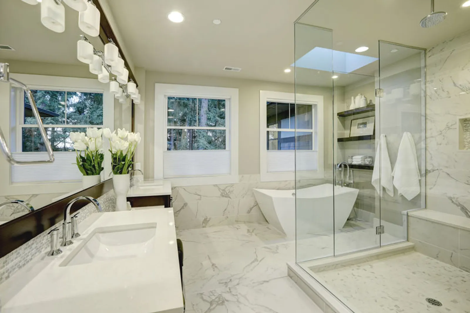 Salle de bain élégante mêlant pierre mate, bois chaleureux et surfaces minérales dans une lumière naturelle douce.