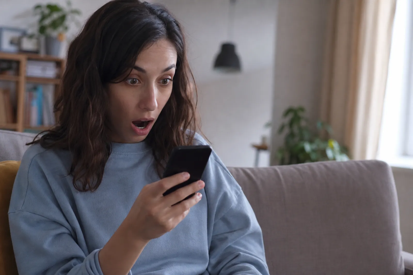 Personne consultant son application bancaire sur smartphone, visage surpris face à un virement inattendu.